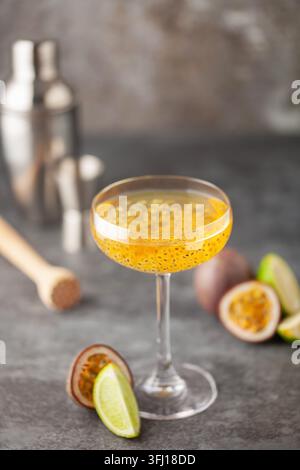 Martini-Cocktail mit Passionsfrucht. Saures alkoholisches Getränk mit frischem Passionsfrucht und Limette, mit Barwerkzeugen. Stockfoto