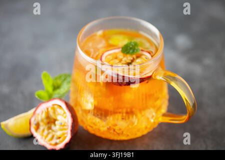 Obsteistee. Erfrischendes Sommergetränk mit Sirup, Passionsfrucht, Limette, Minze und Eis. Glas mit kaltem und gesundem Getränk Stockfoto