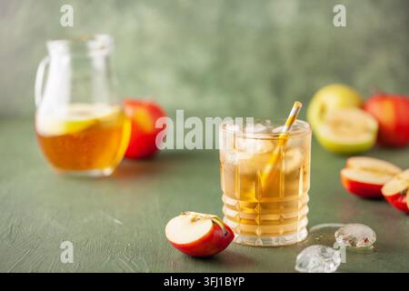 Apfelsaft und Sprudelwasser im Glas. Apfelschorle, deutsches Getränk. Apfel, Eis und Blätter im Hintergrund. Sommerzeit kalt Stockfoto