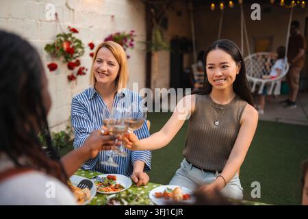 Glückliche Freunde aus verschiedenen ethnischen Gruppen, die während einer Dinner-Party im Freien Weingläser trinken Stockfoto