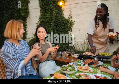 Freunde genießen ein Barbecue im Hinterhof, teilen Essen und Getränke Stockfoto