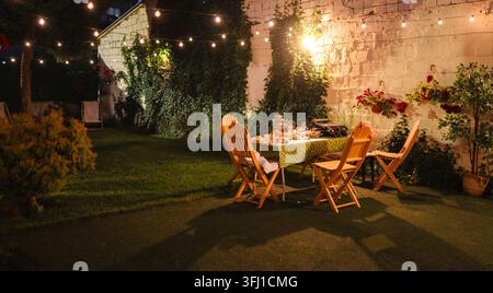 Hinterhof-Dinner-Party mit Lichterketten am Abend Stockfoto