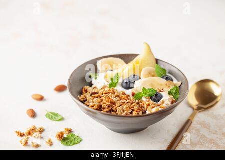 Hausgemachtes knuspriges Müsli, Joghurt, Obst und Beeren in der Schüssel auf weißem Hintergrund. Gesundes Frühstück Stockfoto