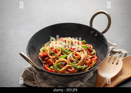 Spaghetti-Pasta mit Garnelen und Gemüse in Wokpfanne auf dem Tisch. Mediterrane Meeresküche Stockfoto