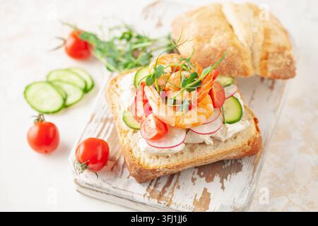 Sandwich mit Gemüse und Garnelen auf einem Holzbrett. Ciabatta-Sandwich Stockfoto