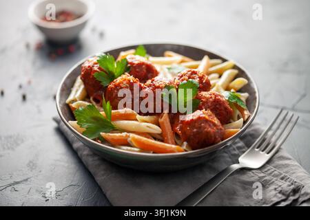 Penne Nudeln mit Fleischbällchen in Tomatensauce und Gemüse in einer Schüssel. Stockfoto