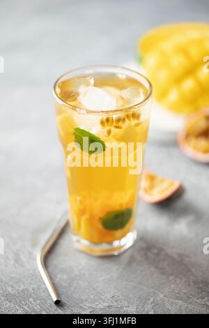 Obsteistee mit Mango, Passionsfrucht und Minze in einem Glasbecher auf dem Tisch. Stockfoto