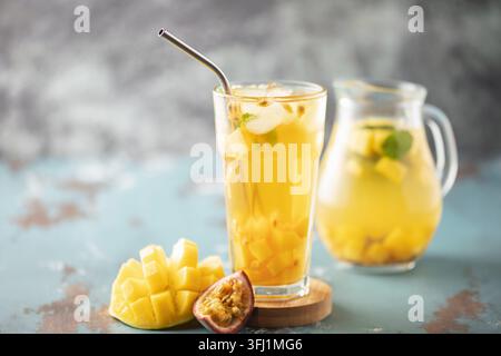 Obsteistee mit Mango, Passionsfrucht und Minze in einem Glasbecher auf dem Tisch. Stockfoto