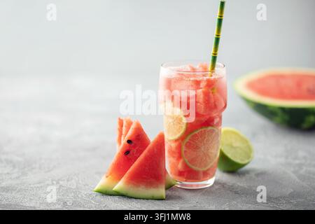 Sommerwasser. Ein Glas leckere kalte Wassermelonen-Limonade mit Limettenscheibe auf dem Tisch Stockfoto