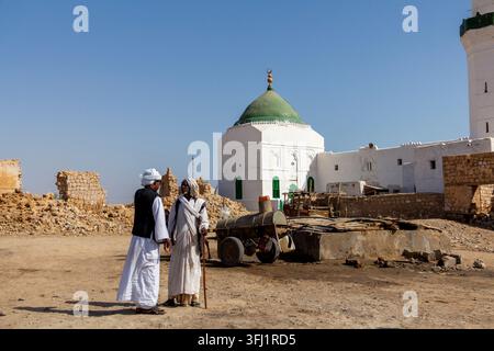 Zwei Männer stehen in der Nähe eines Eselskarren mit Wasserfässern vor einer Kuppelmoschee in der Altstadt, Red Sea State, Suakin, Sudan Stockfoto