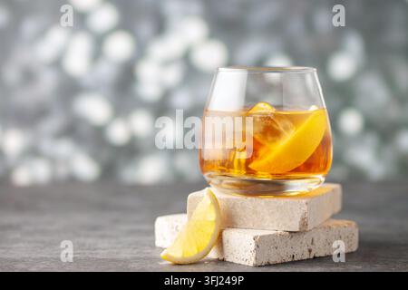 Glas Whiskey mit Zitrone und Eis auf Steinhintergrund. Stockfoto