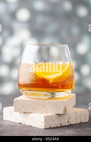Glas Whiskey mit Zitrone und Eis auf Steinhintergrund. Stockfoto