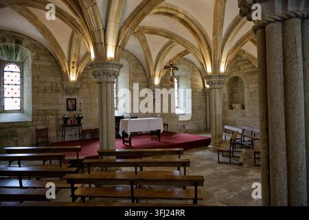 Innenansicht einer Steinkapelle mit Altar, Kruzifix und Kreuzrippengewölbe im Kloster Santa María de Sobrado. Stockfoto
