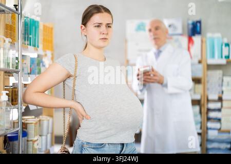 Junge schwangere Frau mit Bauchschmerzen in der Drogerie Stockfoto