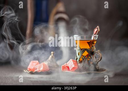 Schwarzer Tee in türkischen Gläsern armudu. Östliche Teezeremonie. Shisha heiße Kohlen auf Shisha-Schüssel, die Wolken aus Dampf machen Stockfoto