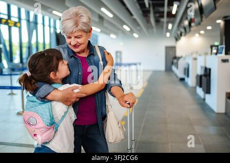 Liebevolle Großmutter umarmt ihre Enkelin am Flughafen vor der Abreise Stockfoto
