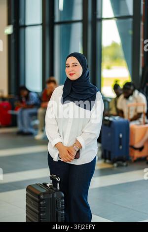 Muslimische Frau mit Hijab wartet auf ihren Flug am Flughafenterminal Stockfoto