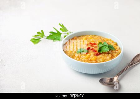 Hausgemachte Erbsenlinsensuppe mit Pfeffer und Petersilie in einer Schüssel auf einem Tisch. Indischer Dahl Stockfoto