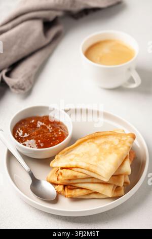 Pfannkuchen oder Crepes auf einem Teller und Marmelade auf dem Tisch. Leckeres Frühstück Stockfoto