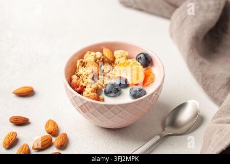 Haferflocken-Müsli mit Joghurt, Beeren, Früchten und Nüssen in einer Schüssel auf dem Tisch. Gesundes Frühstück Stockfoto