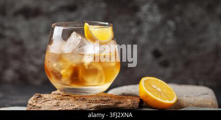 Glas Whiskey mit Zitrone und Eis auf Steinhintergrund. Stockfoto