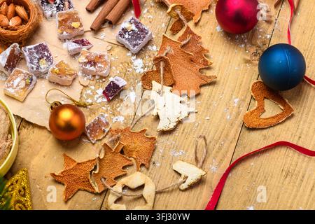 Weihnachthintergrund mit getrockneten Orangenstückchen, Ornamenten und türkischen Süßigkeiten Stockfoto