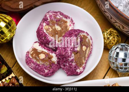 Türkische-Delikatesse-Rollen mit Rosenblättern und Nüssen auf einem weißen Teller mit Weihnachtsschmuck. Stockfoto