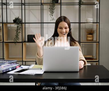 Geschäftsfrau, die einen Laptop benutzt, in die Kamera lächelt, posiert, arbeitet, sitzt am Arbeitsplatz in einem modernen Büro. Stockfoto