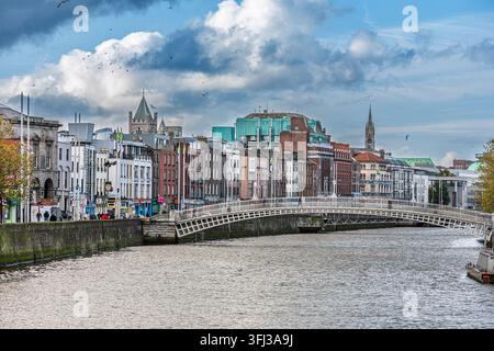 Blick auf Dublins ikonische Ha'Penny Bridge von Westen, zeigt die Gebäude von Wellington Quay entlang des Flusses Liffey unter einem bewölkten Himmel. Stockfoto