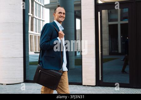 Geschäfts- und Erfolgskonzept: Gutaussehender Mann in modischer Kleidung geht in der Nähe eines modernen Büros Stockfoto