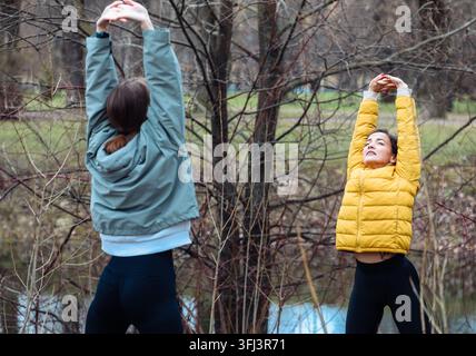 Zwei junge Frauen machen Sportübungen in einem Frühlingspark. Stockfoto