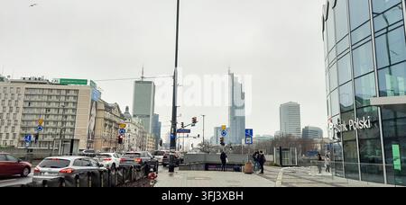 Stadtstraßenansicht von Warschau mit Verkehr, modernen Wolkenkratzern und dem Gebäude der Bank Polski an einem bewölkten Tag - Warschau, Polen - 26. Januar 2023 Stockfoto