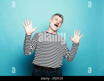 älterer bärtiger Mann, der sich glücklich, überrascht und fröhlich fühlt, mit positiver Einstellung lächelnd, eine Lösung oder Idee realisierend Stockfoto