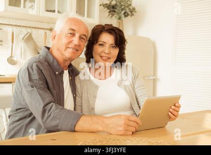 Lifestyle, Familie, Technologie und Senioren-Konzept. Älteres Ehepaar verwendet ein Digitales Tablet zu Hause, in der Küche. Stockfoto