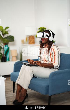 Junge erwachsene Frau, die ein VR-Headset und ein Tablet benutzt Stockfoto