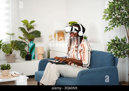 Frau mit Virtual-Reality-Headset, die ein Tablet benutzt Stockfoto