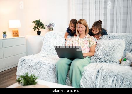 Mutter Töchter arbeiten von zu Hause aus gemeinsam mit Laptop Stockfoto