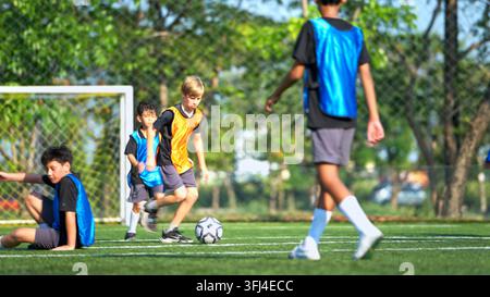 Fußballtrainer trainiert internationale Schulstudenten auf dem Feld Stockfoto
