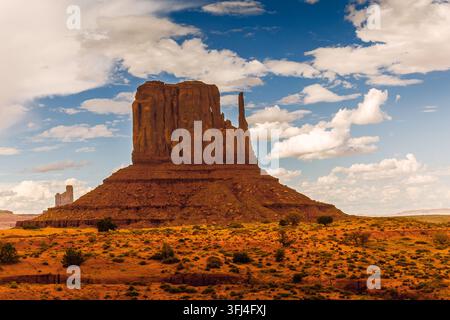 Ein breites, horizontales Landschaftsfoto, das eine Nahaufnahme des West Mitten Butte im Monument Valley einfängt. Der massive rote Sandstein bildet Stockfoto
