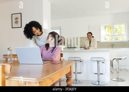 Afroamerikanische Familie lehnt sich an, führt Jugend an, die am Esstisch mit Laptop und Smartphone arbeitet Stockfoto