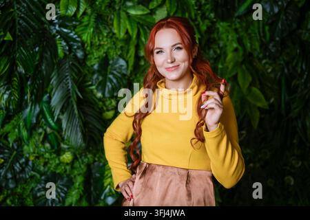 Lächelnde rothaarige Frau mit einer verspielten Locke Stockfoto
