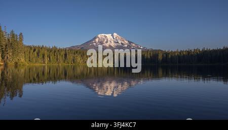 Mount Adams spiegelt sich im ruhigen Wasser des Takhlakh Lake im Bundesstaat Washington, USA, wider, umgeben von immergrünem Wald. Stockfoto