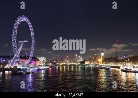 London, Vereinigtes Königreich - 30. Dezember 2025: Nachtansicht des London Eye über der Themse. Stadtlichter spiegeln sich auf der ruhigen Wasseroberfläche. Boote fahren Stockfoto