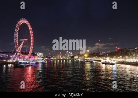 London, Vereinigtes Königreich - 30. Dezember 2025: Nachtansicht des London Eye über der Themse. Stadtlichter spiegeln sich auf der ruhigen Wasseroberfläche. Boote fahren Stockfoto
