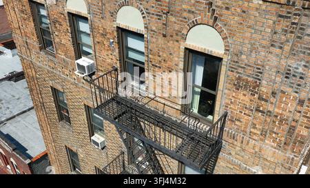 Feuertreppe außerhalb eines alten Backsteinwohngebäudes in New York City. Klimageräte und Fenster. Luftbild-Einstellung. Stockfoto