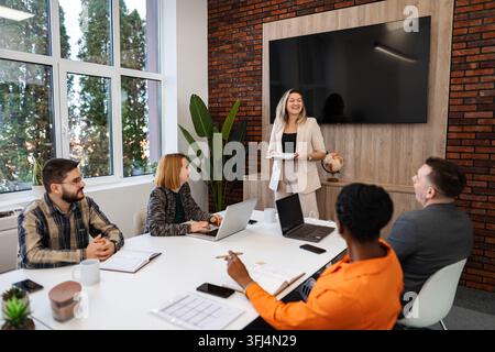 Geschäftsfrau führt eine Präsentation vor einem diversen Team in einem modernen Büro Stockfoto