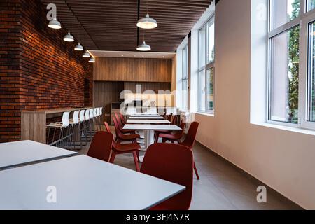 Modernes Bürokantineninterieur mit Ziegelwand und roten Stühlen Stockfoto