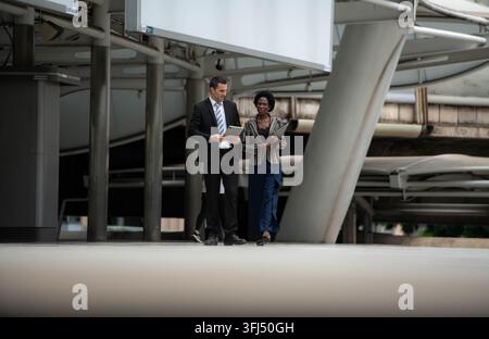 Geschäftsleute gehen zusammen in einem modernen Stadtteil und besprechen die Arbeit Stockfoto