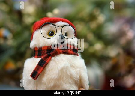Plüsch-Eulen-Spielzeug in einem roten Hut und Schal mit Brille für Weihnachten Stockfoto