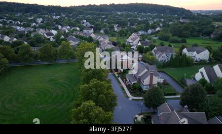 Grünes Grasfeld eines Parks in einem amerikanischen Vorstadtwohnviertel zur Sonnenzeit. Idyllische Landschaft mit Wohngebiet und Straße. Überwachsene Bergkette Stockfoto
